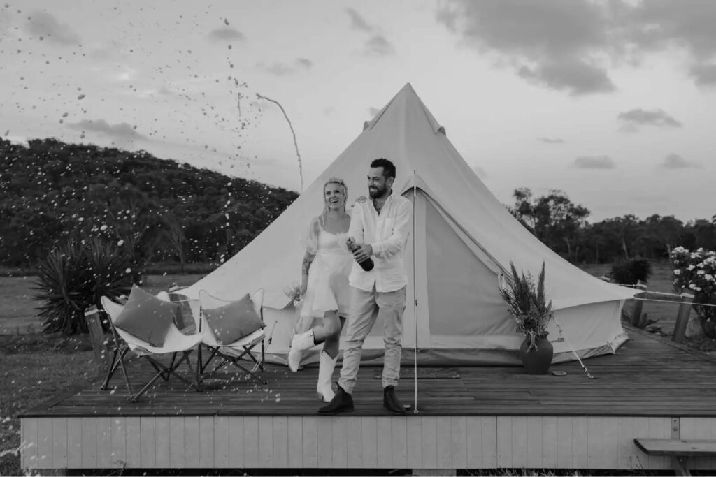 Couple celebrating beside a luxury glamping bell tent at The Salty Lime Co