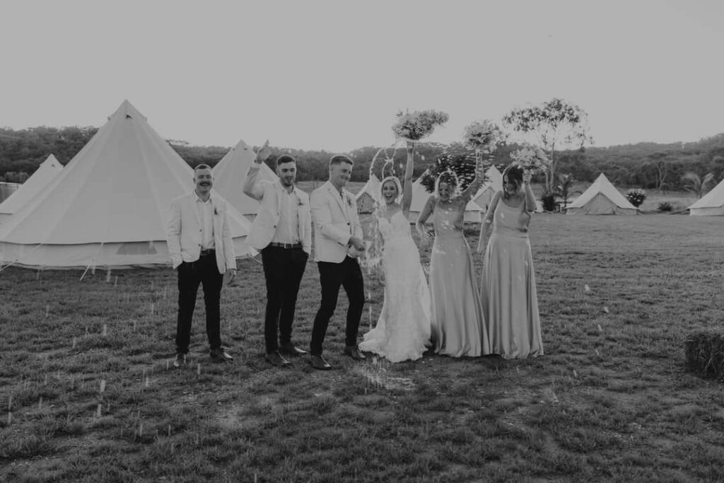 Wedding party celebrating among the glamping bell tents
