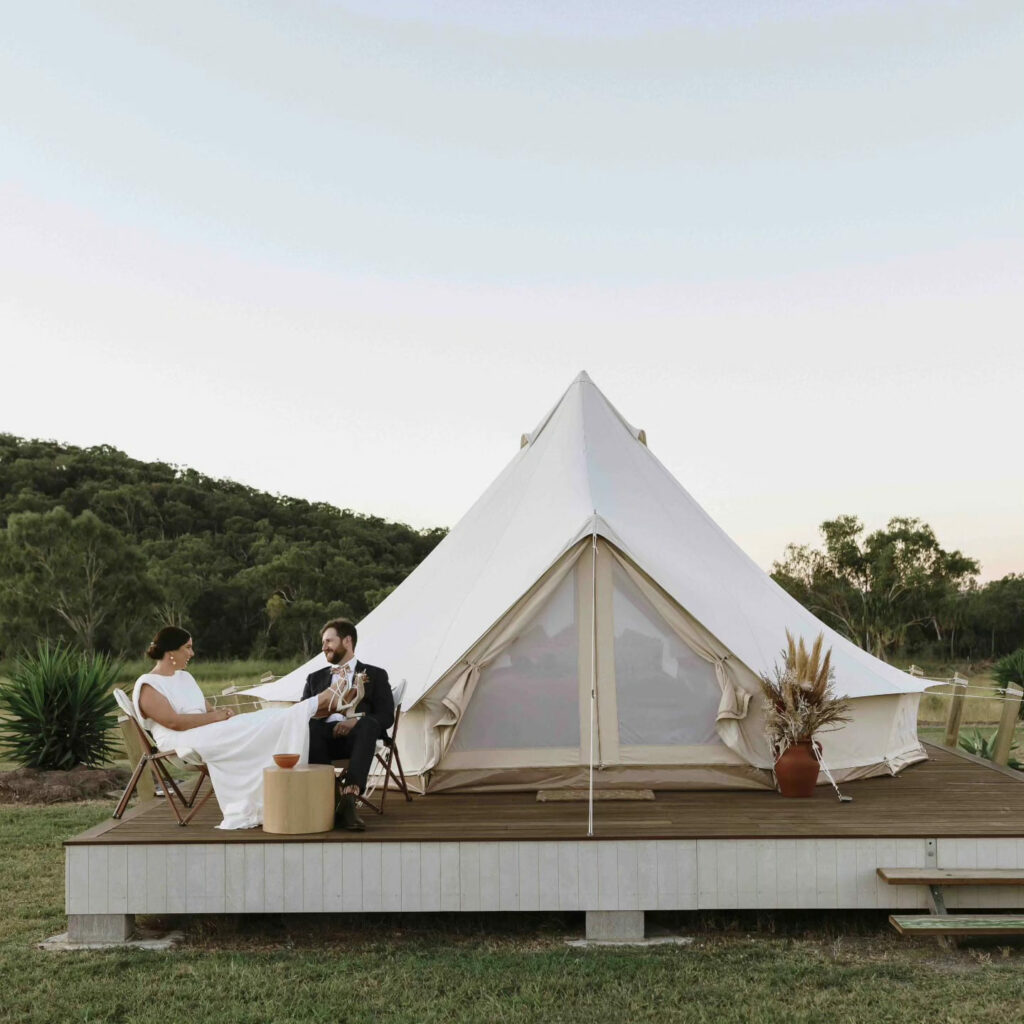 Couple seated on the private deck outside their glamping tent