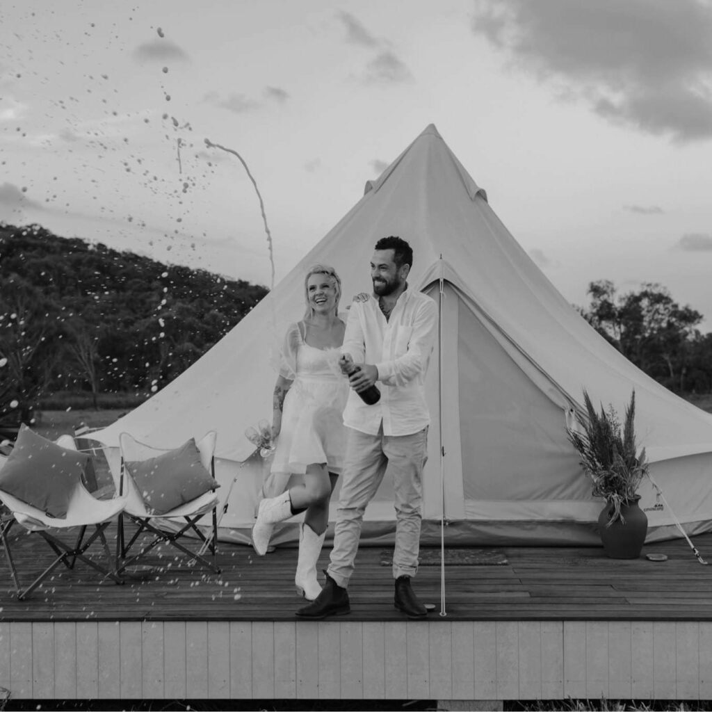 Newlyweds celebrating beside a glamping bell tent