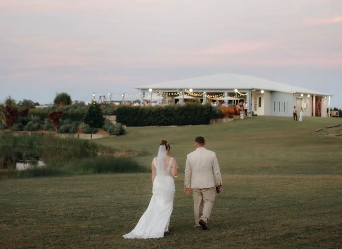 Newlywed couple walking across the lawn towards The Salty Lime Co venue