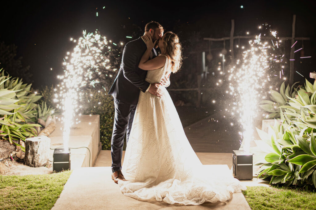 Newlyweds sharing a kiss beneath wedding sparklers