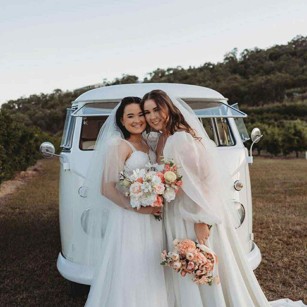 Bride with flowers beside a vintage wedding van