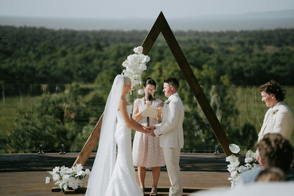 Outdoor wedding ceremony with timber triangle arbour and mountain views