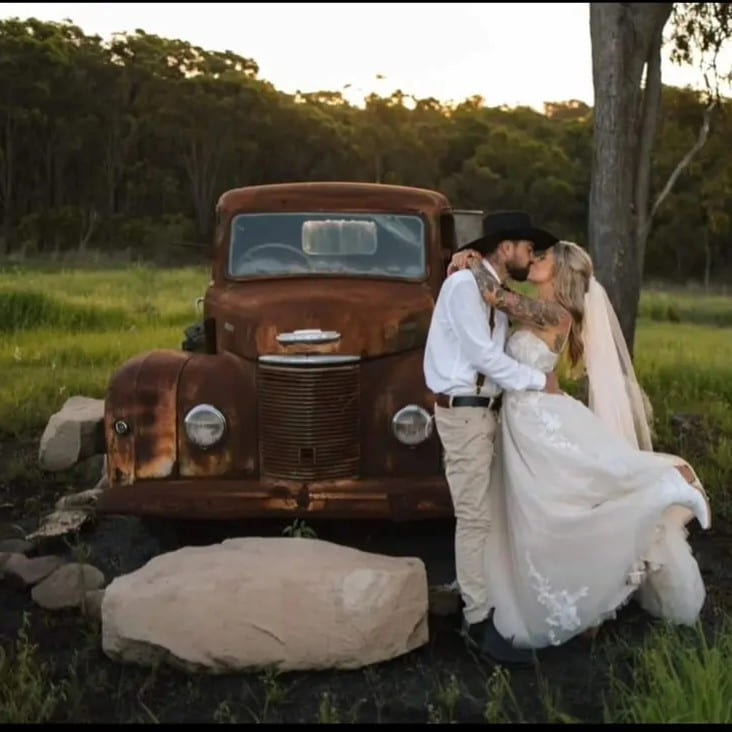 Newlyweds beside a vintage truck at a country wedding