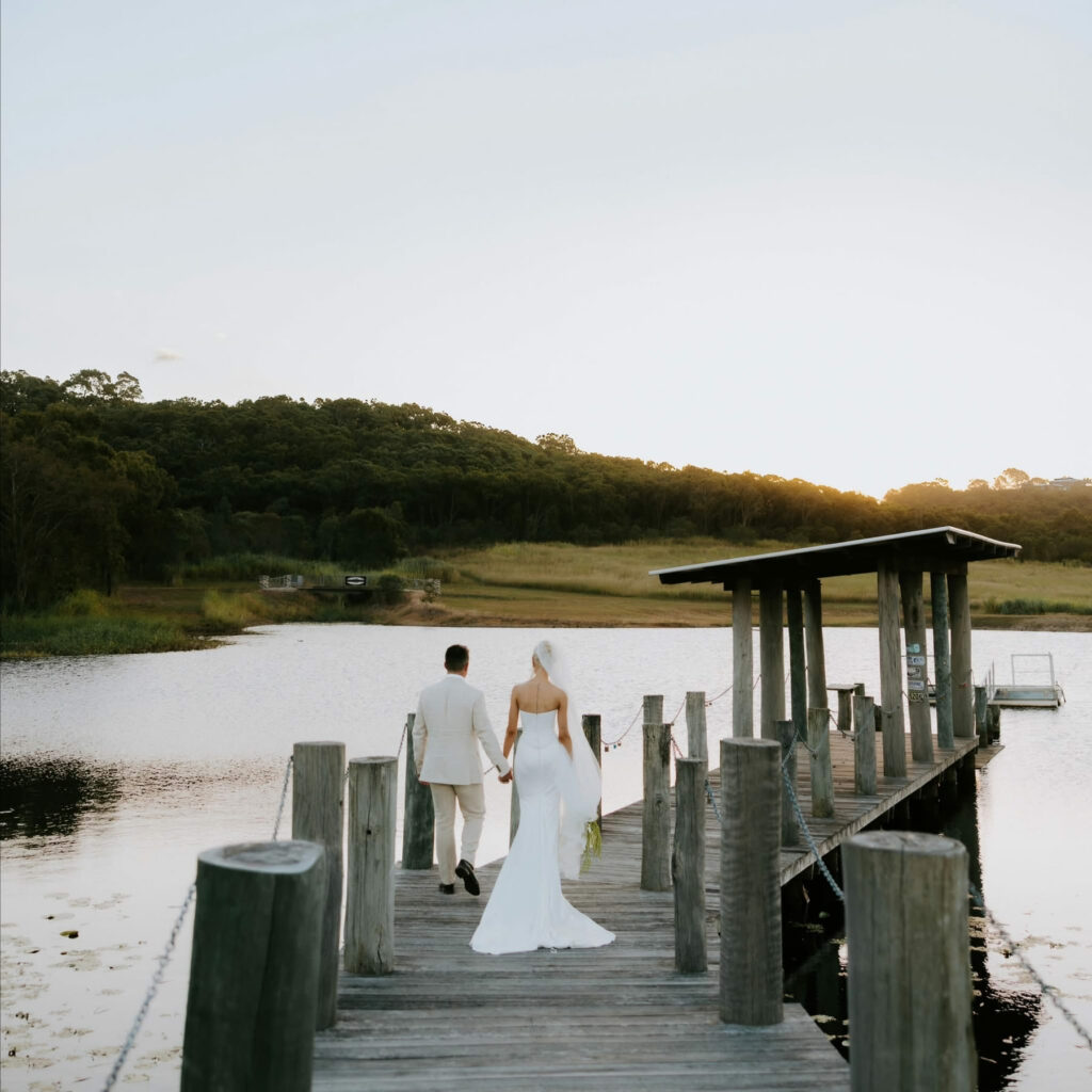 Wedding couple walking together along the lakeside jetty